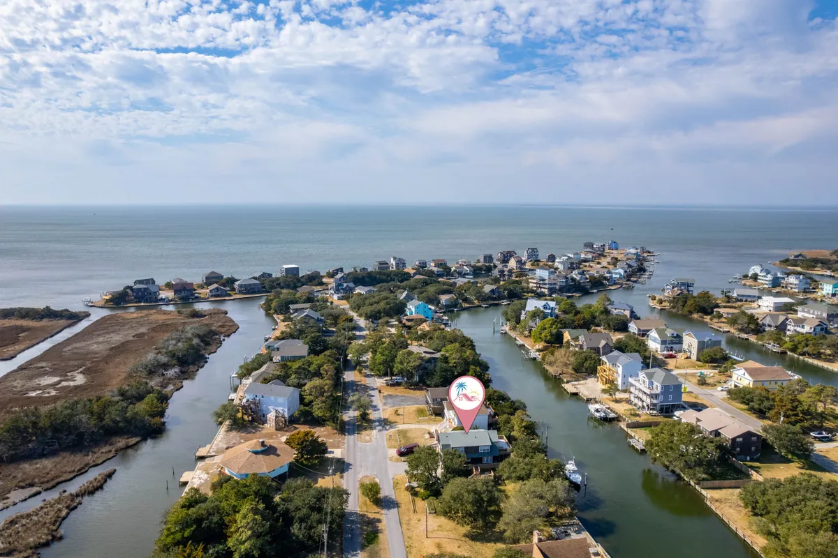 A wide view of a serene canal lined with waterfront houses and docks, with boats visible and open water stretching toward a marina. The scene captures both the excitement of water sports and the peacefulness of quiet canal mornings.