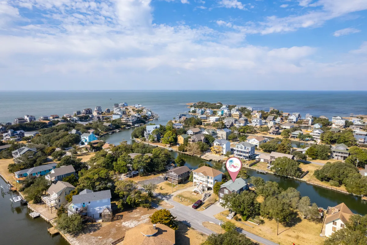 A tranquil view of calm waterways bordered by green vegetation and residential homes, with the colors of sunset reflecting on the water. The image feels serene and emphasizes quiet moments spent close to nature, right at the edge of the marsh.