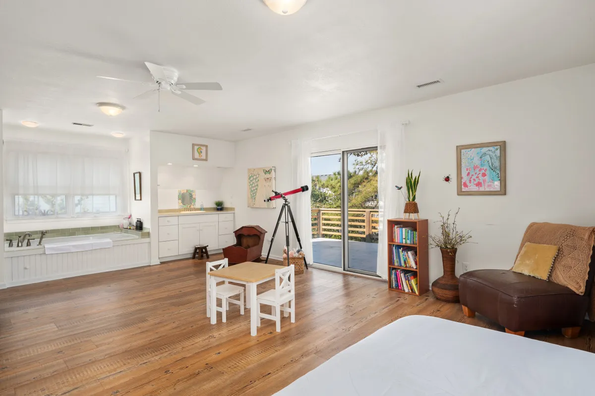 An inviting interior scene featuring a telescope by large windows, cozy seating, and artistic decor. The telescope hints at family stargazing nights, while the comfortable space suggests board games, reading, or movie nights—activities highlighted as family amenities in the section.