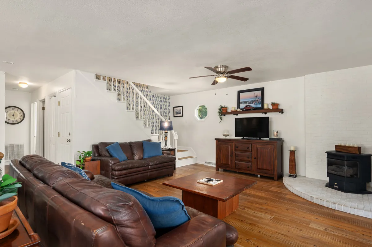 A welcoming living room with leather sofas, a wooden coffee table, TV stand, and a fireplace sets a cozy scene for family gatherings, movie nights, and quiet mornings. Decor and lighting enhance the inviting mood.