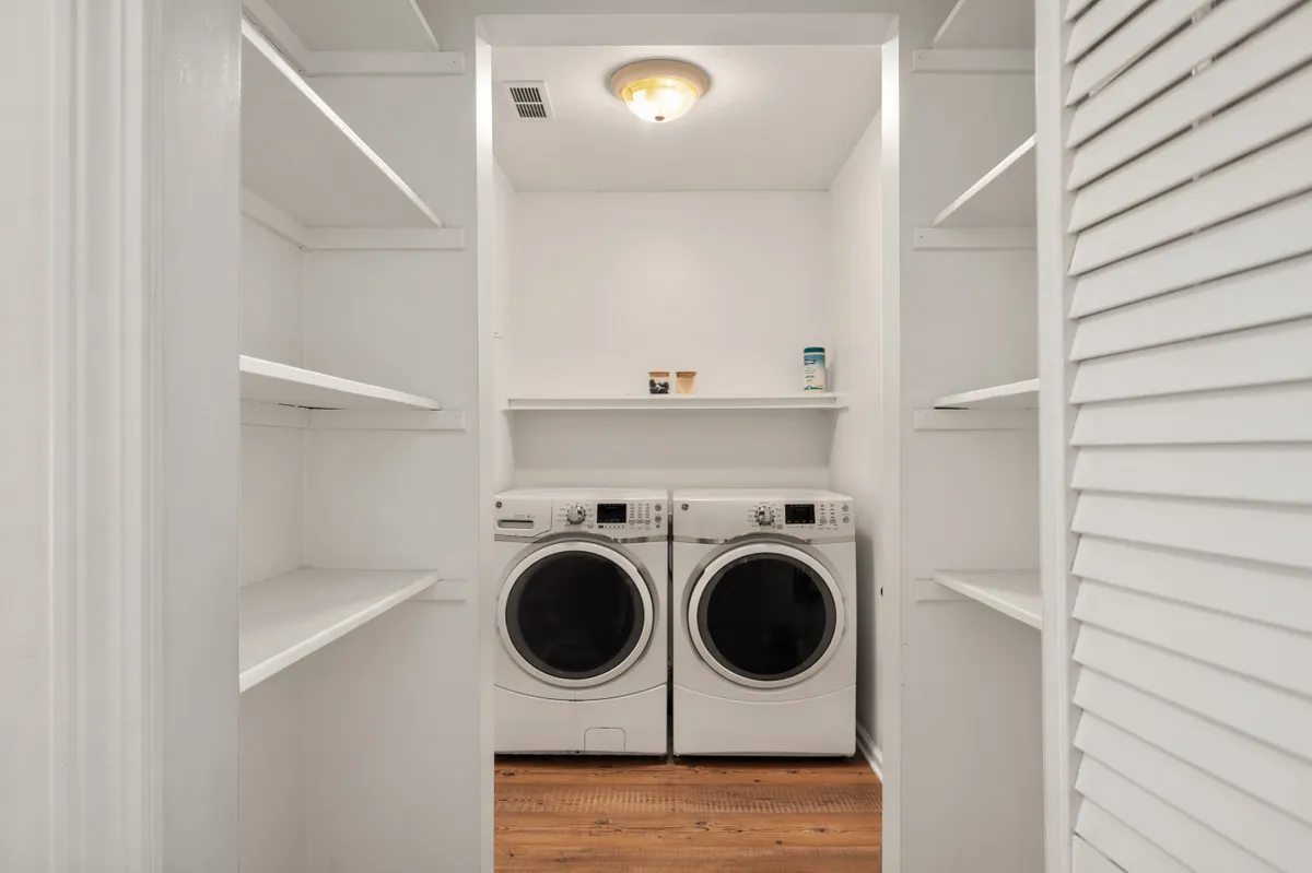 A practical and tidy laundry area featuring a washing machine, dryer, and shelves for storage. The room is well-lit and organized, communicating ease and comfort for guests staying longer or with family needs.