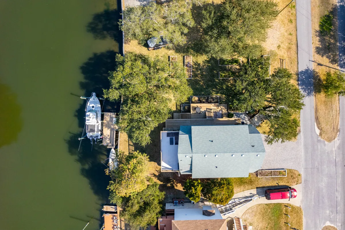 A tranquil exterior scene showing a house right on the waterfront, with a private dock, a boat moored, and lush trees nearby. The water glows with sunset light, creating an inviting atmosphere for launching watercraft or relaxing by the shore.